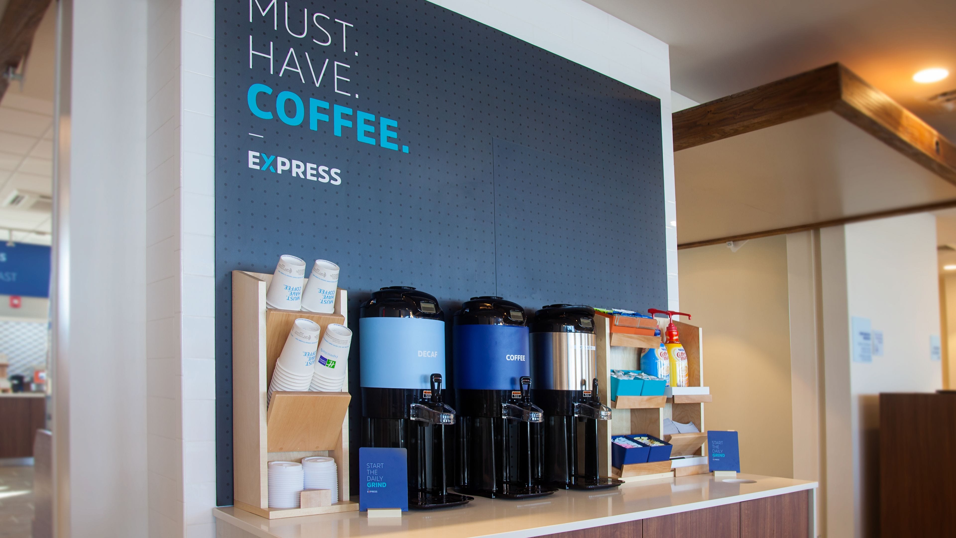 Una estación de café con varias cafeteras y vasos desechables.