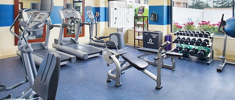 A gym with various exercise equipment, including treadmills, an elliptical, and dumbbells.