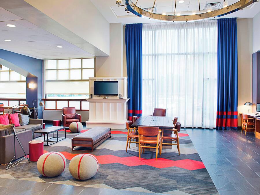 En moderne hotellobby med et stort siddeområde, et mødebord og et fjernsyn.