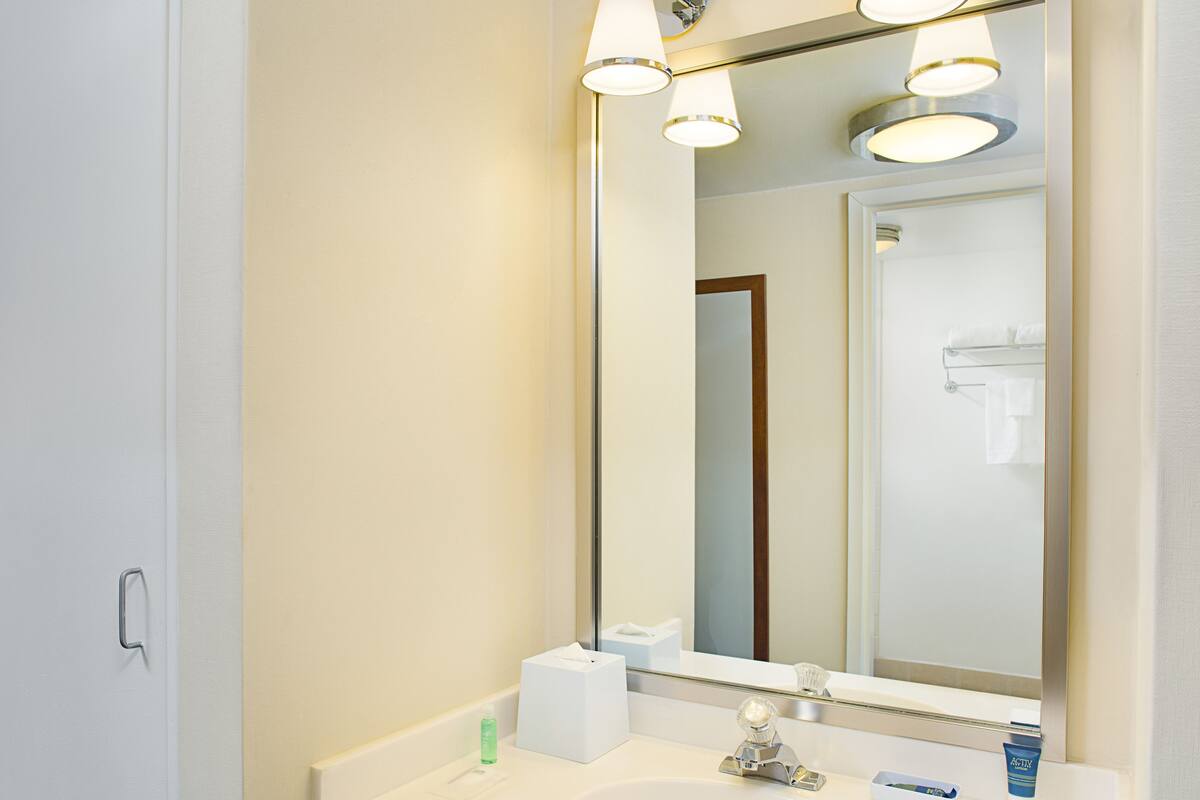 A bathroom with a white sink, a mirror, and a towel rack.
