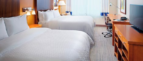 Habitación de hotel con dos camas, un escritorio, una silla, un televisor y una ventana con cortinas.