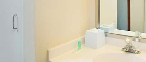 Un baño con un lavamanos blanco, un espejo y una lámpara sobre el espejo.