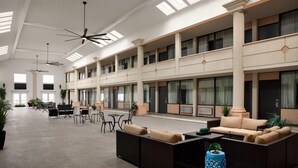 A spacious lobby with high ceilings, large windows, and multiple seating areas. - Super 8 by Wyndham Meadowlands (Carlstadt)