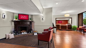 A hotel lobby with a fireplace, red seating, a reception desk, and a sign indicating free Wi-Fi availability. - Red Roof Inn Norwich (Norwich)