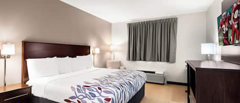 Une chambre d’hôtel comprenant un lit, des tables de chevet, un bureau, une chaise, une fenêtre avec des rideaux et un téléviseur à écran plat.