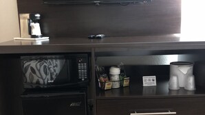 A compact kitchenette with a microwave, coffee maker, and storage drawers. - Red Roof Inn Norwich (Norwich)