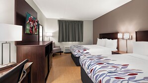A hotel room with a bed, bedside tables, a desk, a chair, a TV, and a window with curtains. - Red Roof Inn Norwich (Norwich)