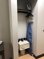 A small room with a white cabinet, a blue ironing board, and a wall-mounted ironing board.