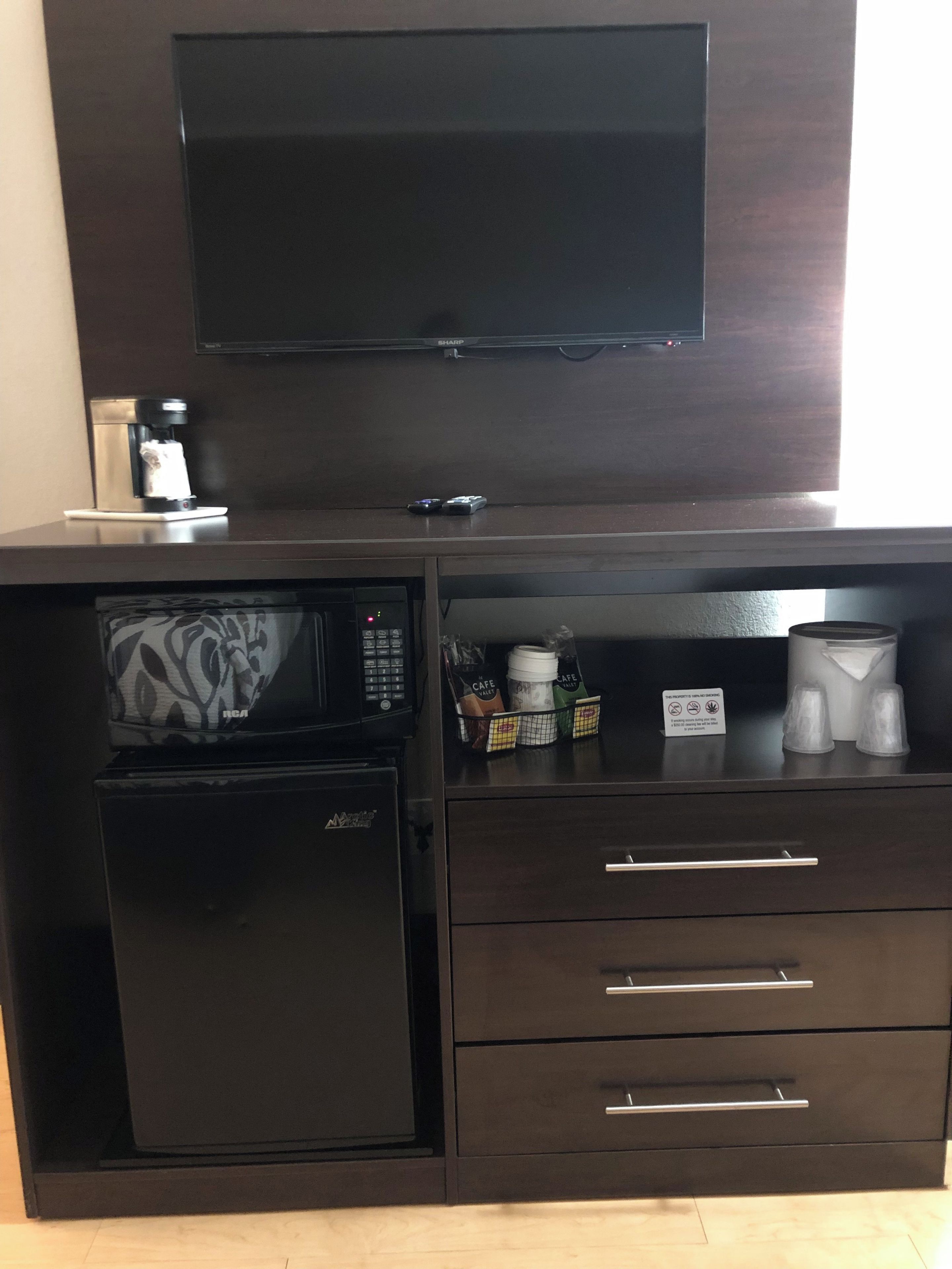 Une petite cuisine équipée d’un four à micro-ondes, d’une machine à café et de tiroirs de rangement.