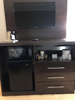 Una kitchenette compacta con microondas, cafetera y cajones de almacenamiento.