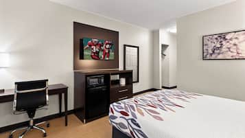 A hotel room with a bed, desk, chair, and a television mounted on the wall.