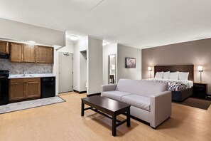 A compact living space with a kitchenette, a sofa, a bed, and a bedside table. - Red Roof Inn Norwich (Norwich)