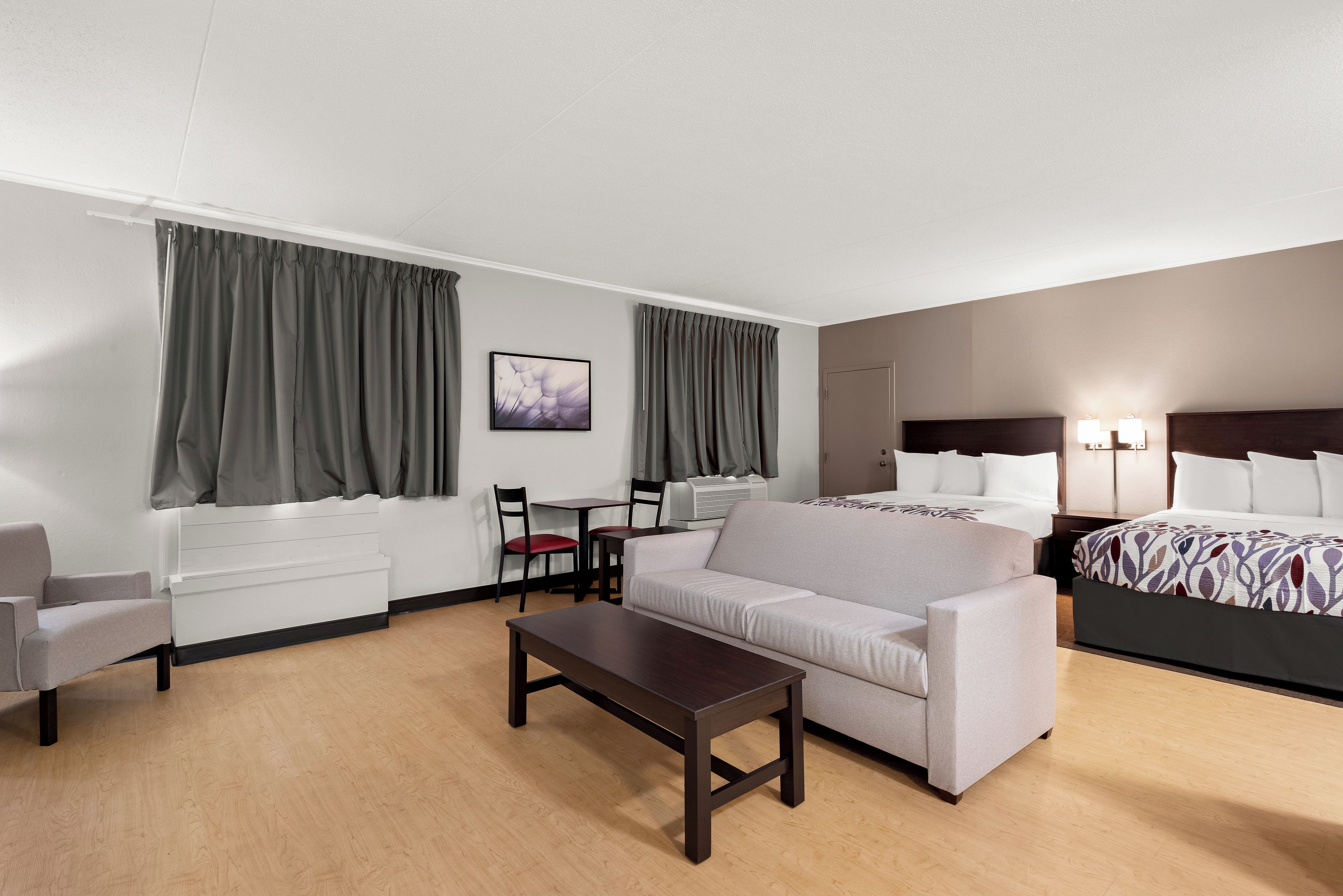 A hotel room with a bed, a sofa, a table, a chair, and a desk.