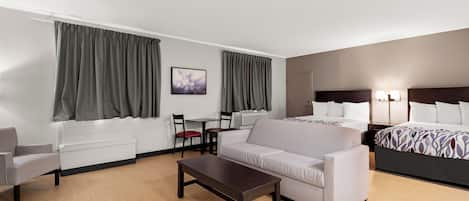 A hotel room with a bed, a sofa, a table, a chair, and a desk.