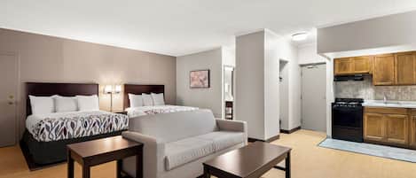 Une chambre d’hôtel comprenant un lit, un canapé, une table et une kitchenette.