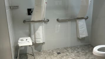 A bathroom with a shower, a toilet, and a small step stool.