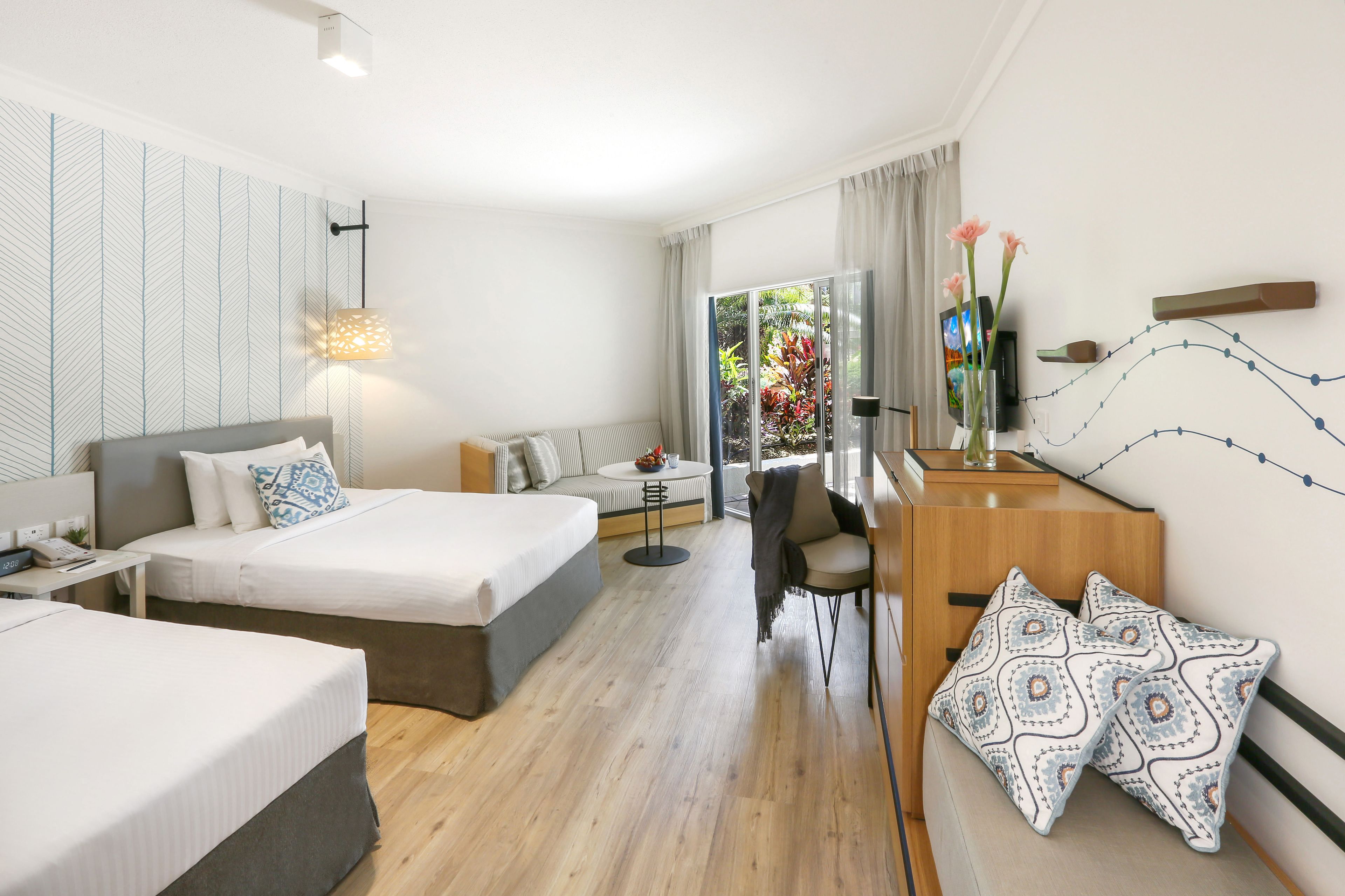 A hotel room with a large bed, a desk with a chair, a small table, and a TV.