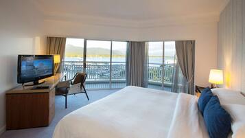 Une chambre d’hôtel avec un grand lit, un bureau avec une télévision, une chaise et une vue sur le bord de l’eau.