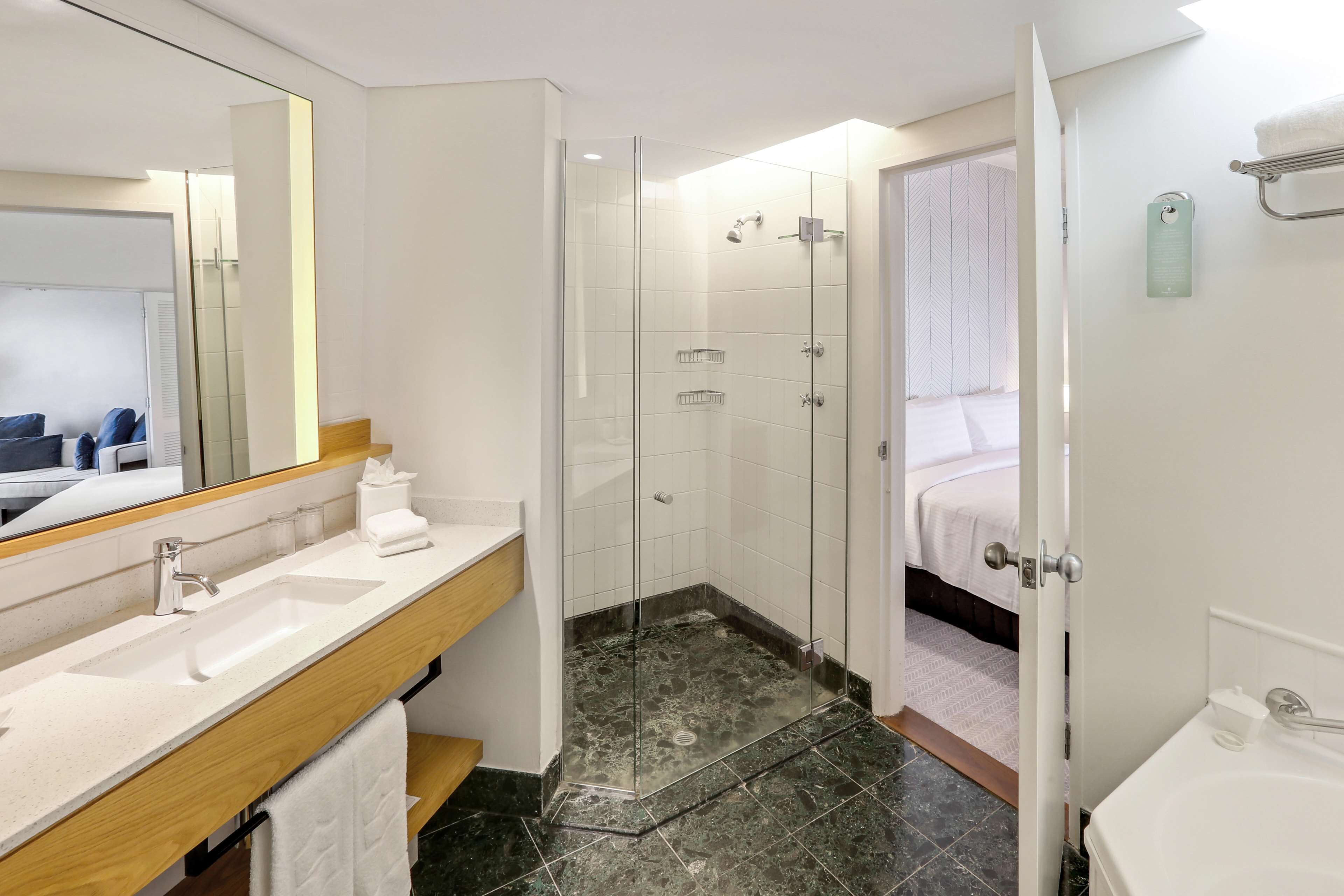 A modern bathroom with a glass-enclosed shower, a sink with a wooden vanity, and a separate bathtub area.