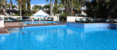 Una piscina al aire libre, sombrillas, sillones reclinables de piscina