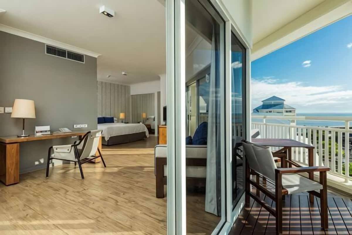 Una habitación de hotel con balcón, cama, escritorio y una silla.