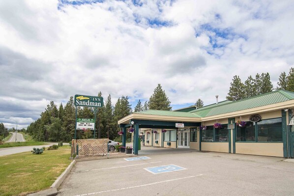 A building with a green roof and a sign that reads "Inn Sandman." There are handicapped parking spaces and a covered entrance.