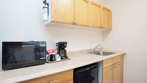 A compact kitchenette with a microwave, coffee maker, and sink.
