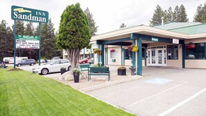 A hotel with a sign reading "Inn Sandman," a parking lot, and a building entrance with a covered area.