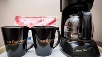 A coffee maker and two branded mugs on a table.