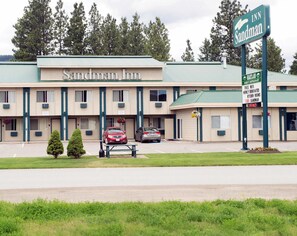 A Sandman Inn with a green roof, two parking spaces, and a sign indicating a Heartland Family Restaurant.