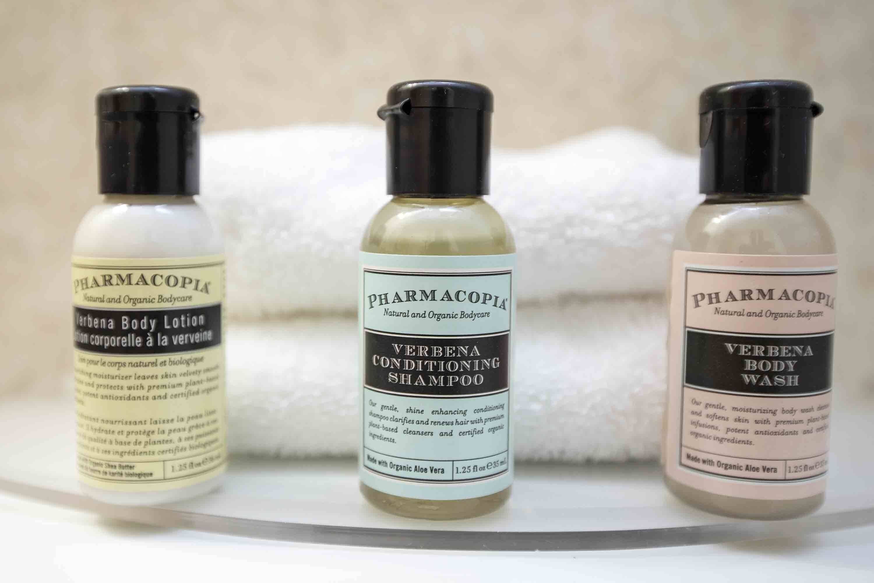 Trois bouteilles de produits de soins corporels de la marque Pharmacopia, disposées sur une étagère.
