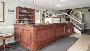 A reception area with a wooden reception desk, a glass display case, a staircase, and a framed picture on the wall.