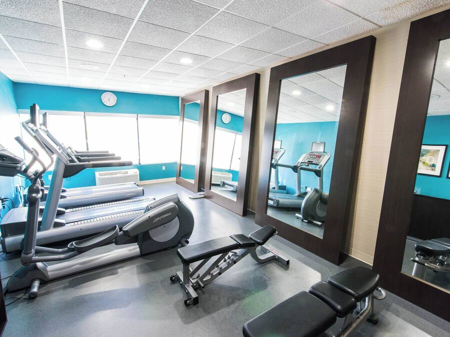 A gym with treadmills, a bench press, and a mirrored wall.