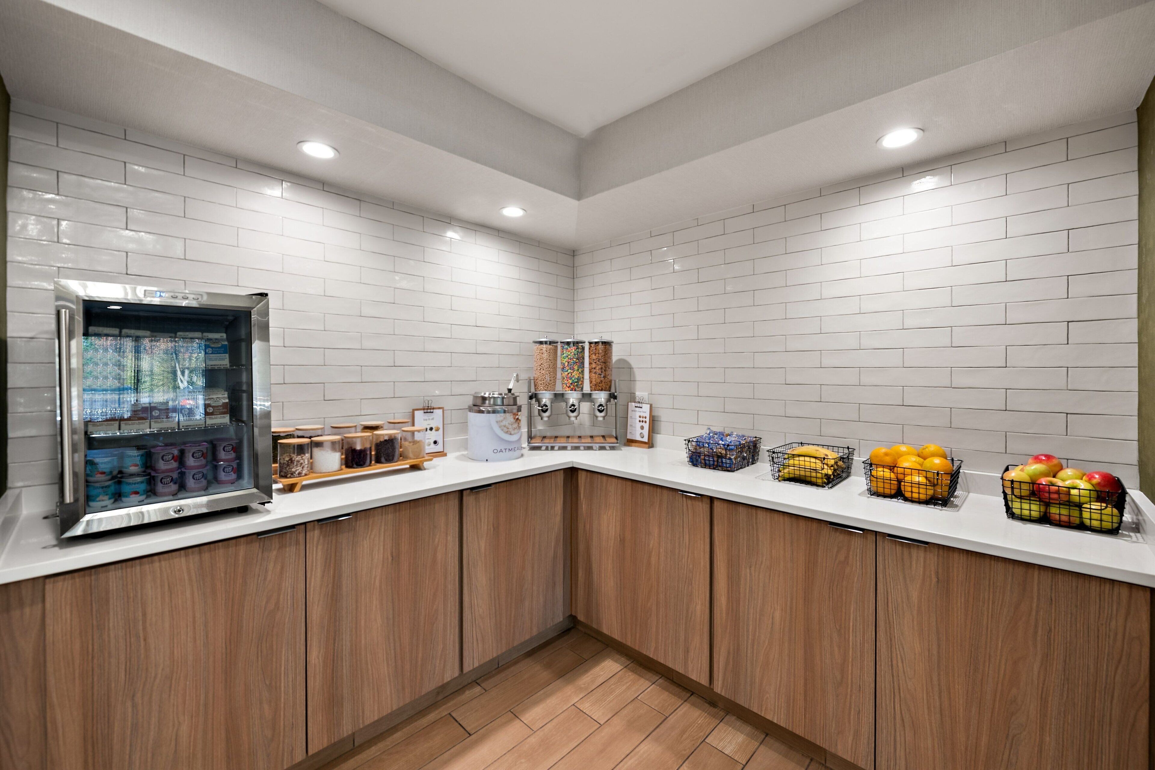 A kitchen area with a refrigerator, coffee machine, and various food items on the counter.