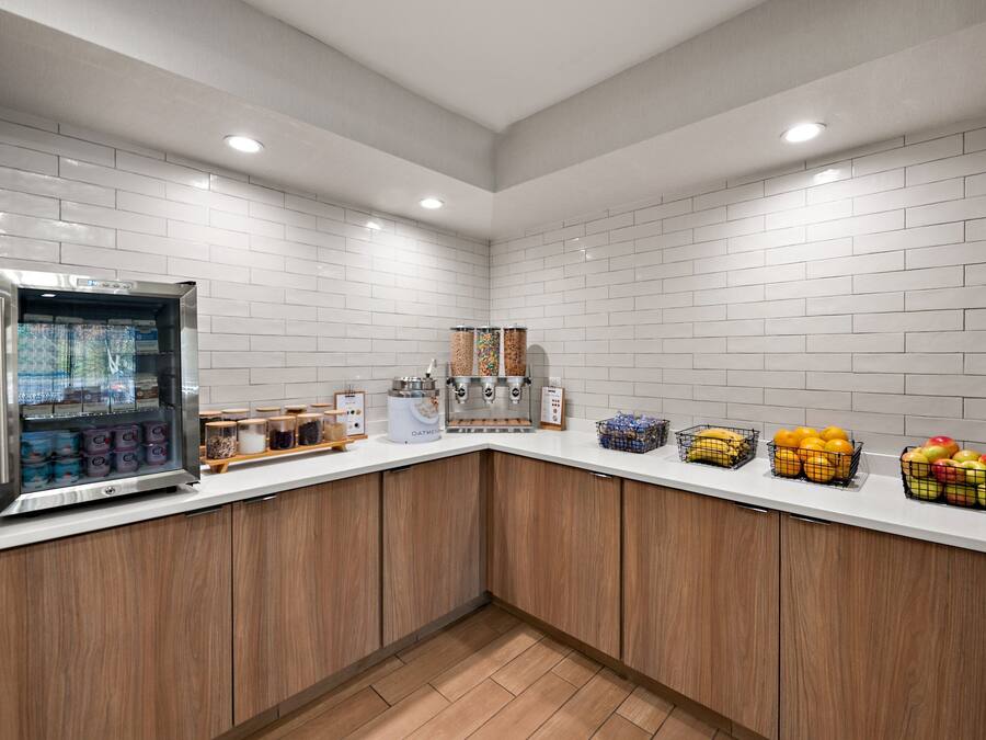 A kitchen area with a refrigerator, coffee machine, and various food items on the counter.