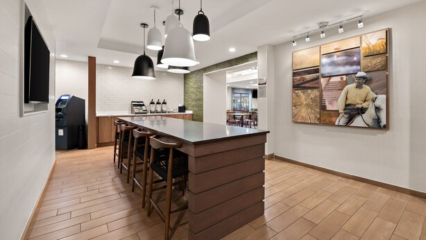 A modern kitchen with a central island, bar stools, pendant lighting, and a large wall-mounted artwork. - Fairfield Inn and Suites By Marriott Chesapeake (Chesapeake)