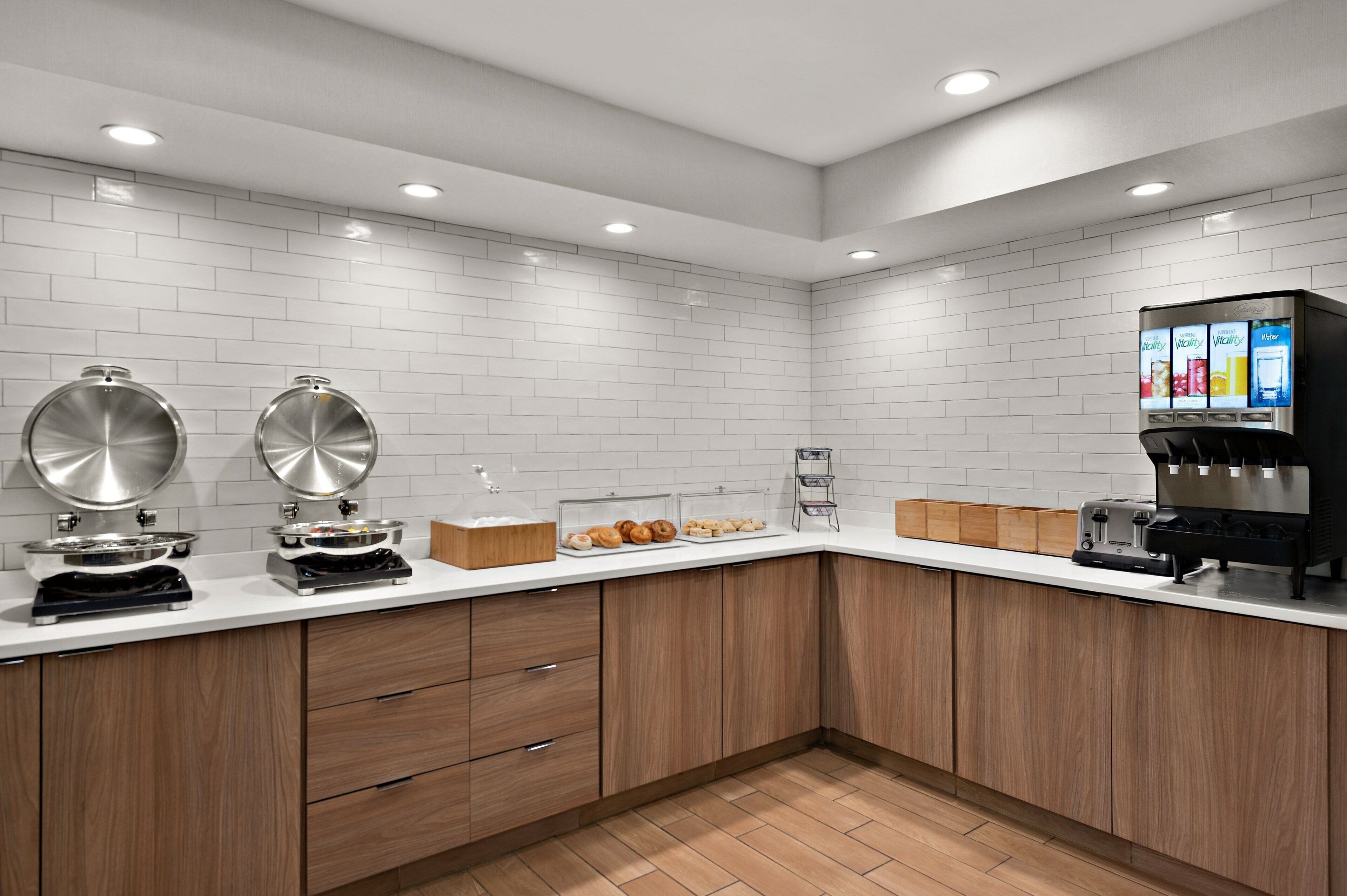 Uma cozinha moderna com azulejos brancos tipo metrô, armários de madeira, uma cafeteira e uma torradeira.