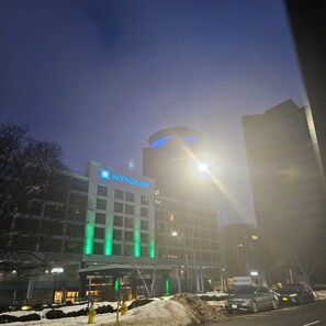 A Wyndham hotel with a modern design, featuring a prominent blue sign and green lighting accents.