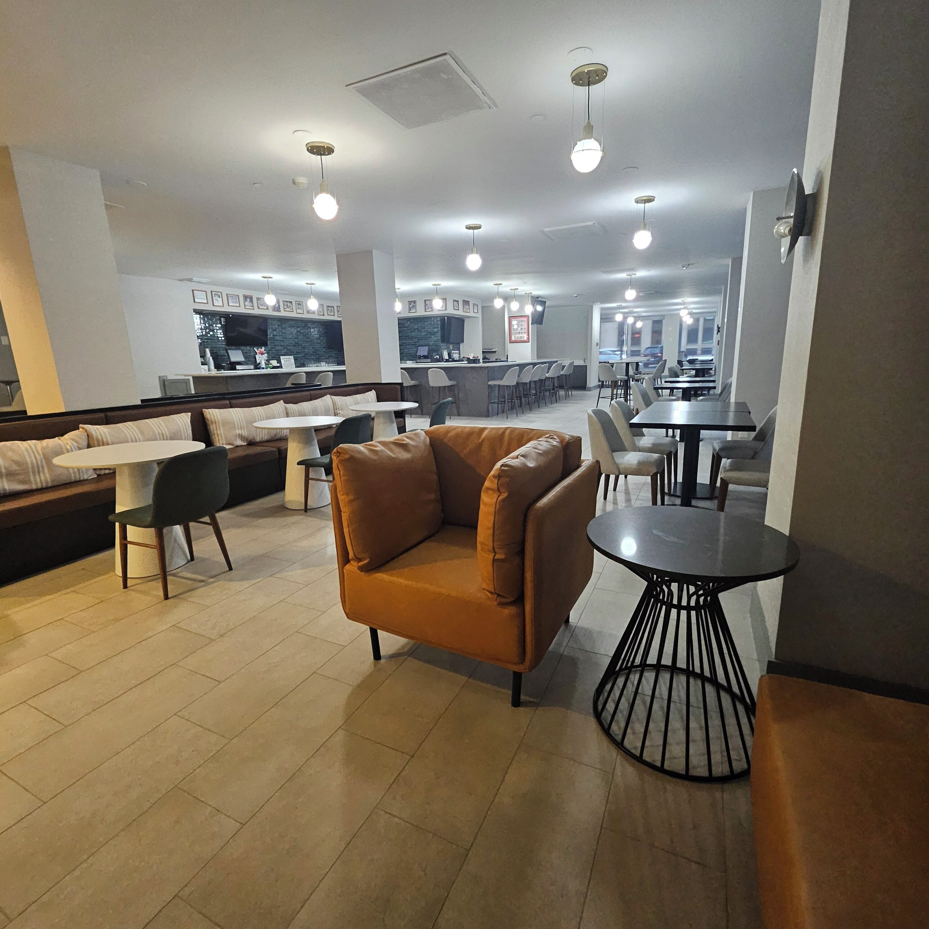 A modern interior with seating areas, a bar, and a kitchen visible in the background.
