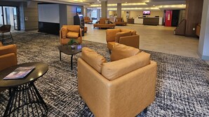 A spacious lobby with leather sofas, a reception desk, and an ATM. - Wyndham Rochester Downtown (Rochester)