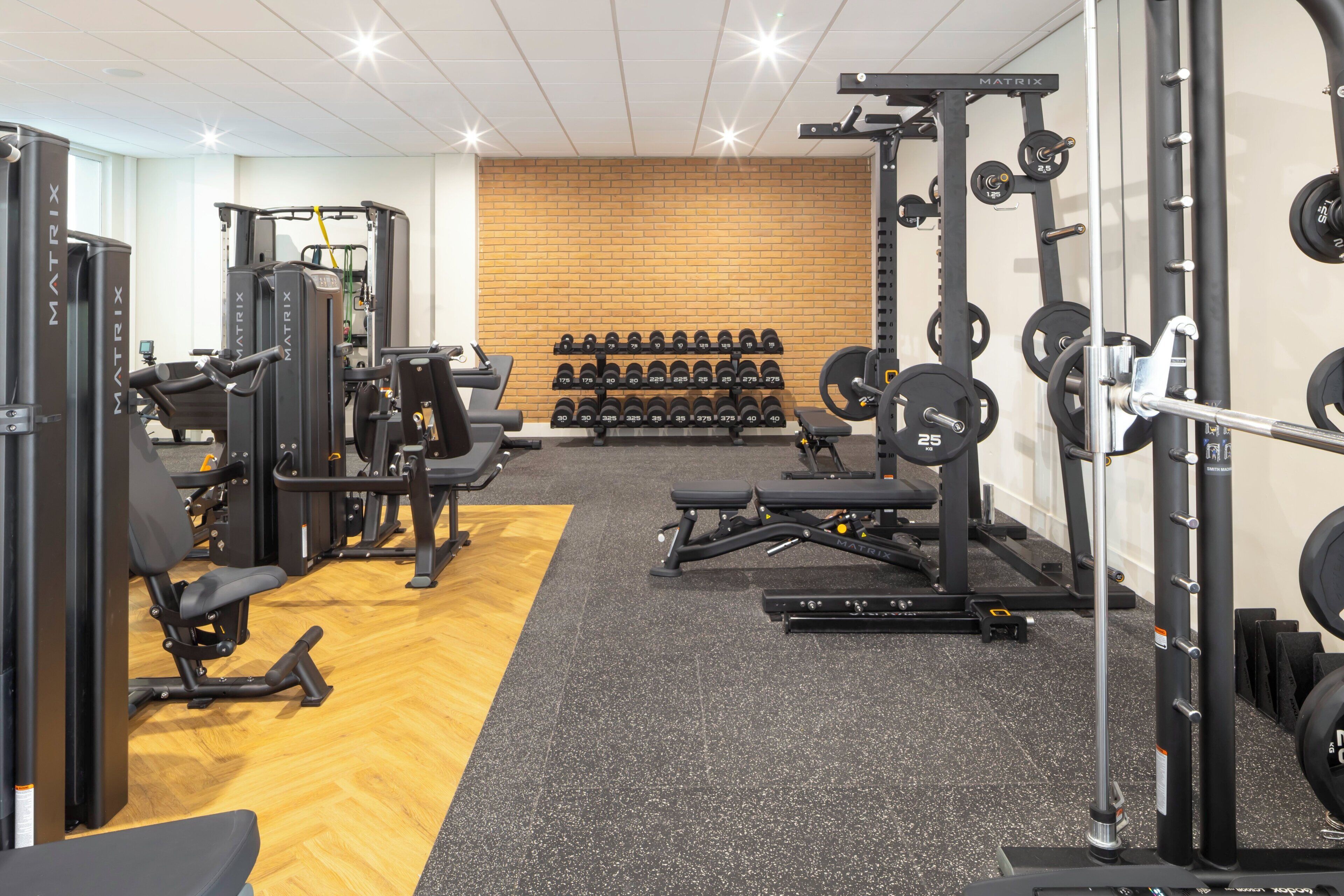 A gym with various exercise equipment, including weight machines, free weights, and a bench.