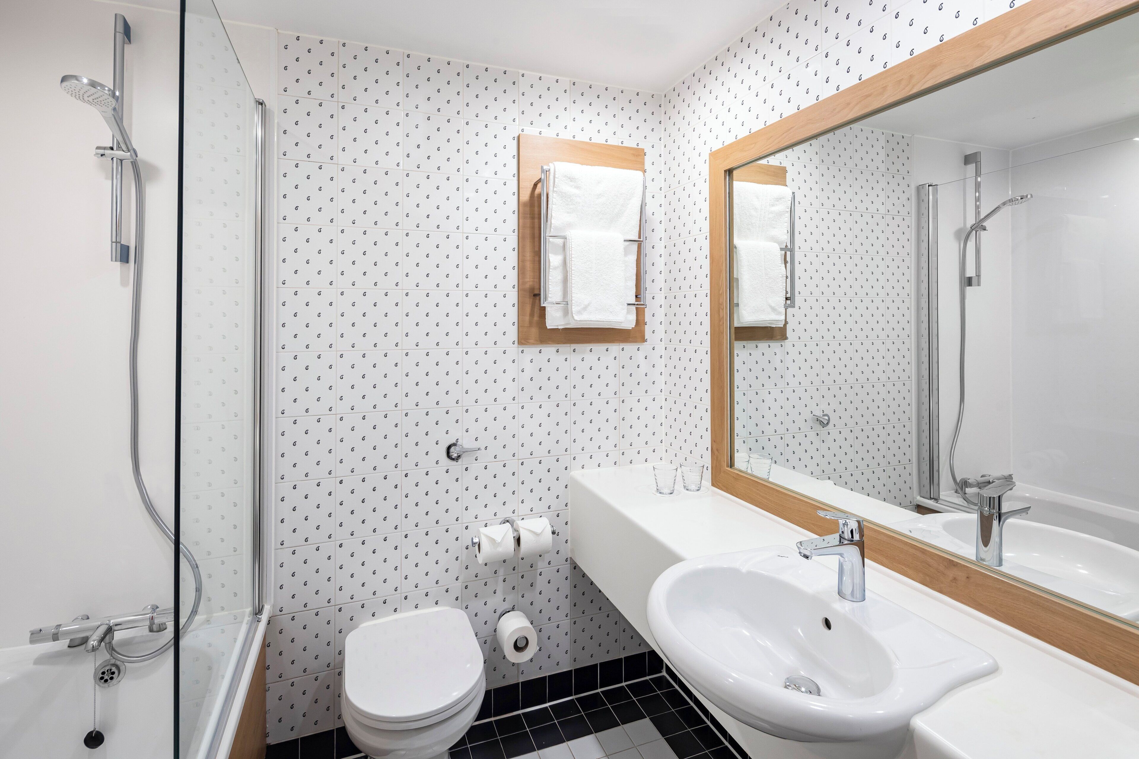 A modern bathroom with a shower, toilet, and sink.
