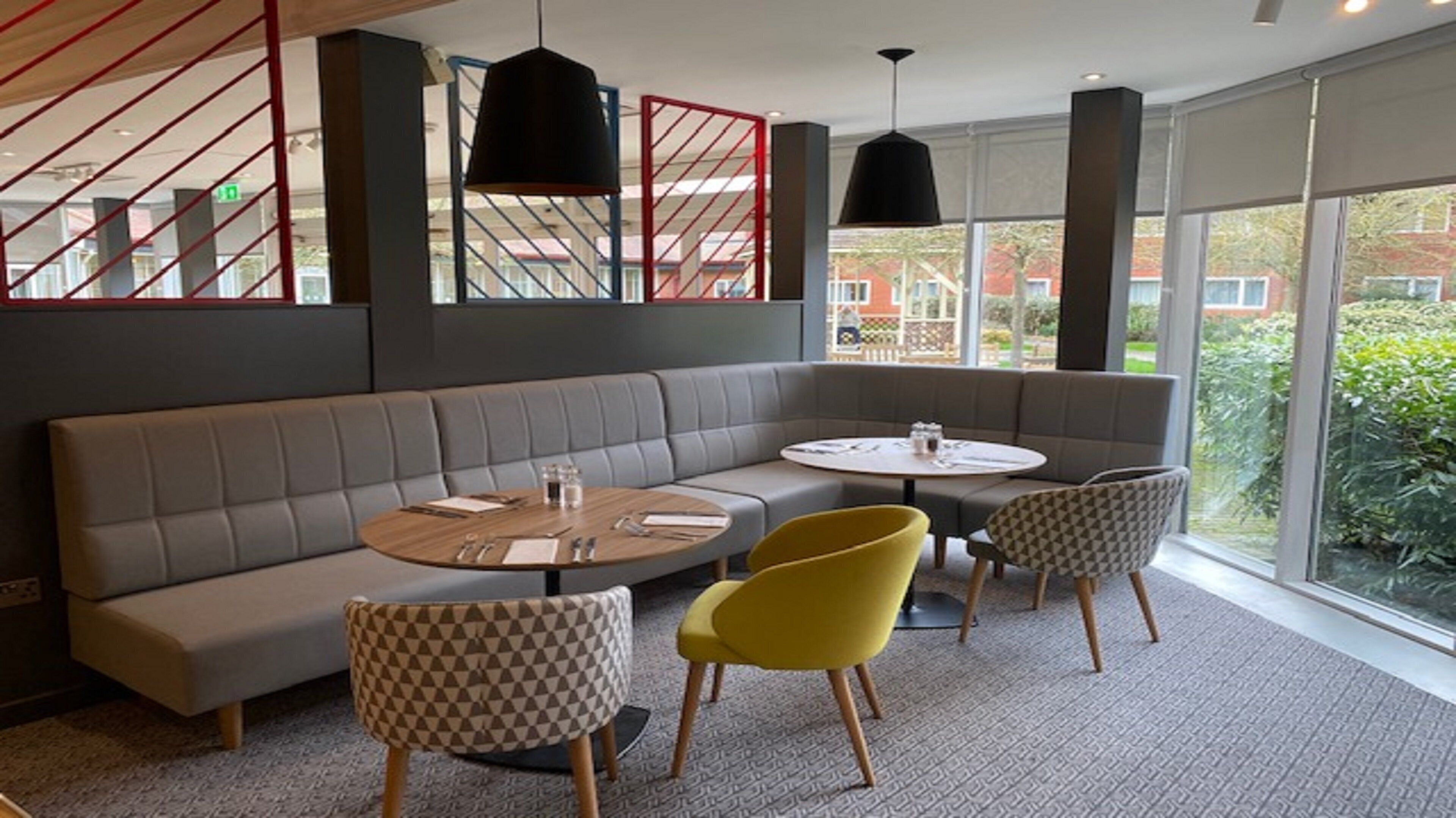 A modern interior with a curved sofa, round tables, and checkered chairs.