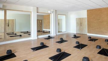 Un gimnasio con colchonetas de ejercicio, pesas libres y una pared de ladrillo.