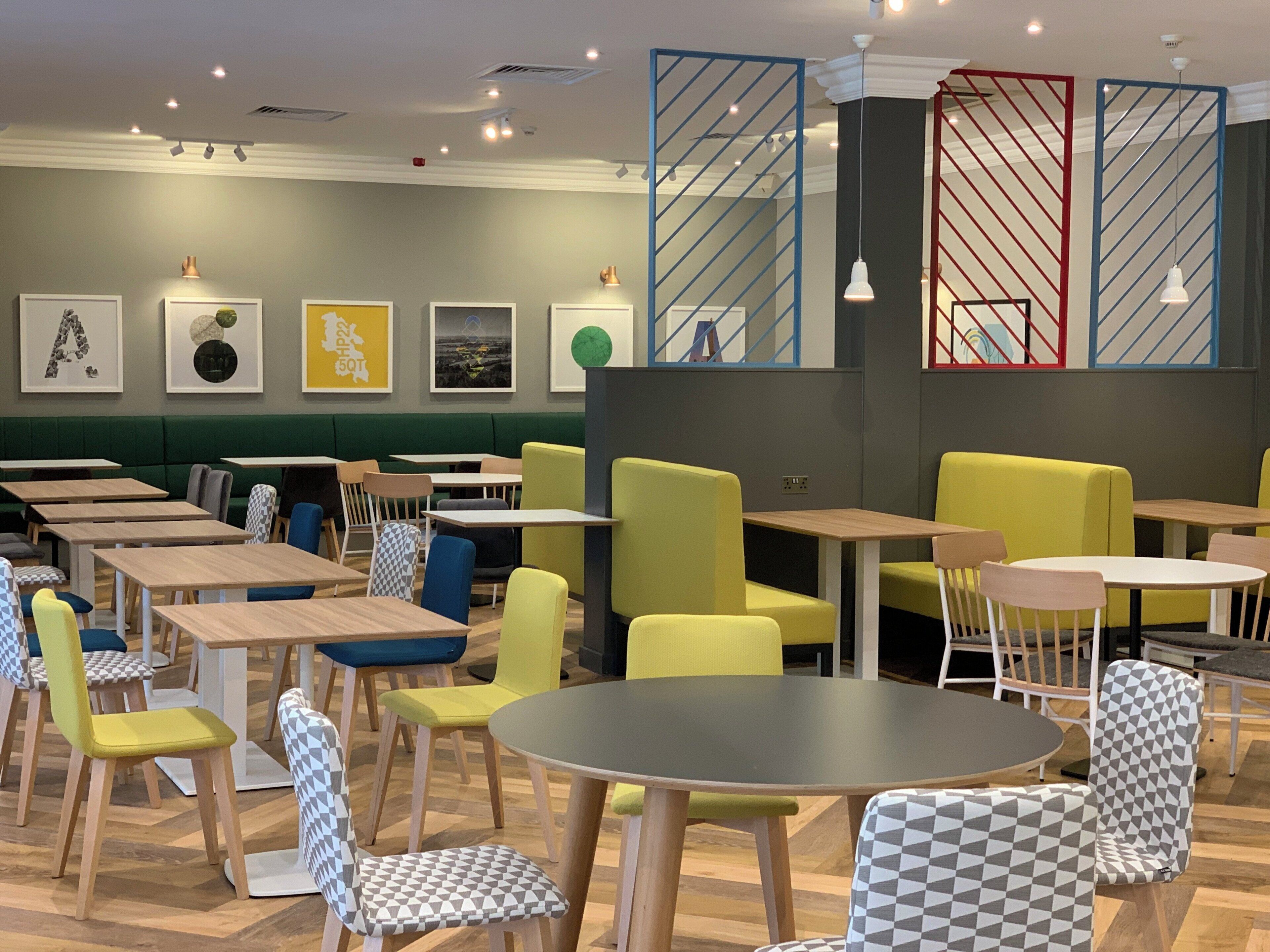 Een restaurant met verschillende zithoeken, waaronder perken en tafels, en diverse stoelontwerpen.