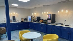 A restaurant with blue cabinets, yellow chairs, and a white table.