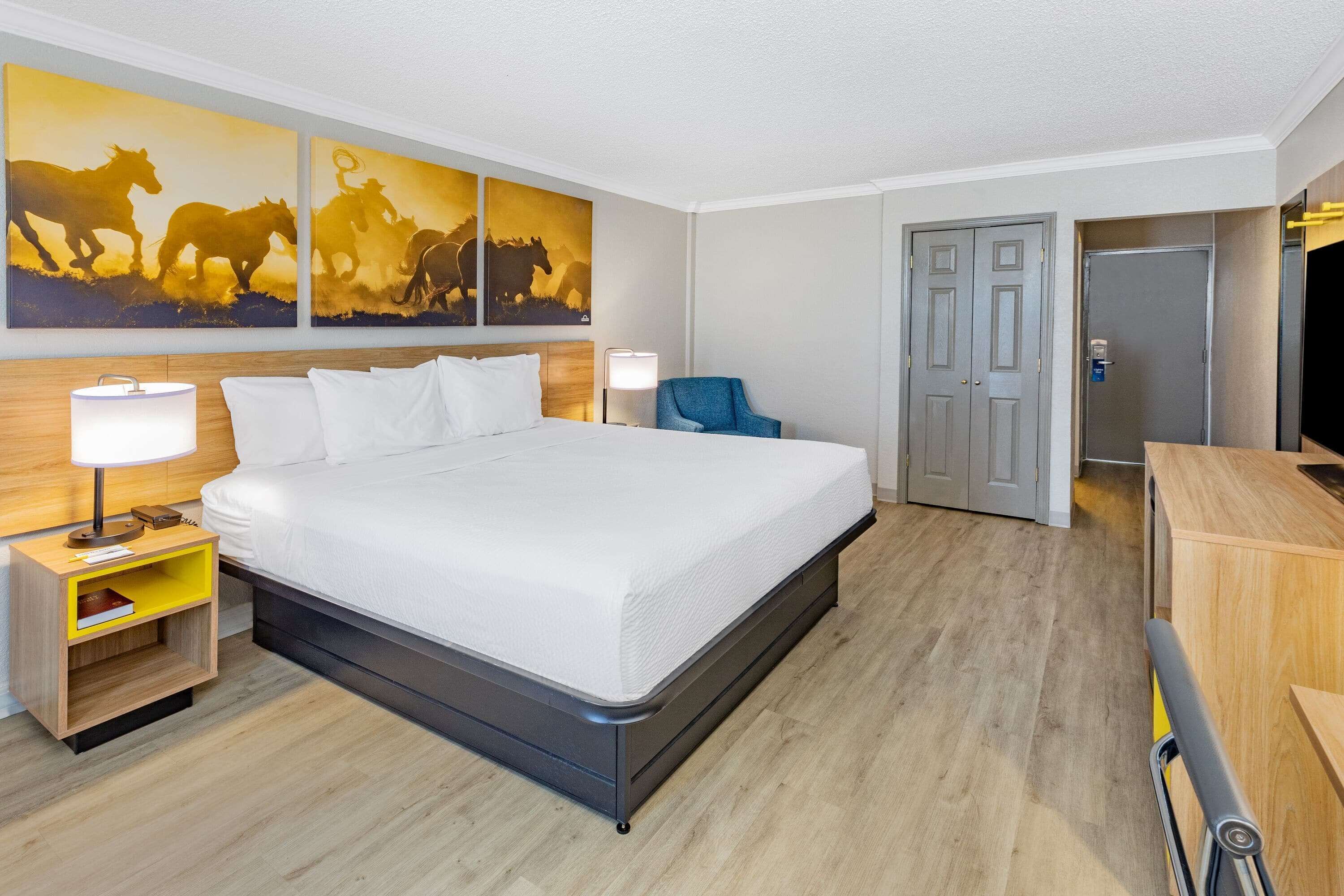 A hotel room with a large bed, bedside tables, a chair, a desk, and a TV.