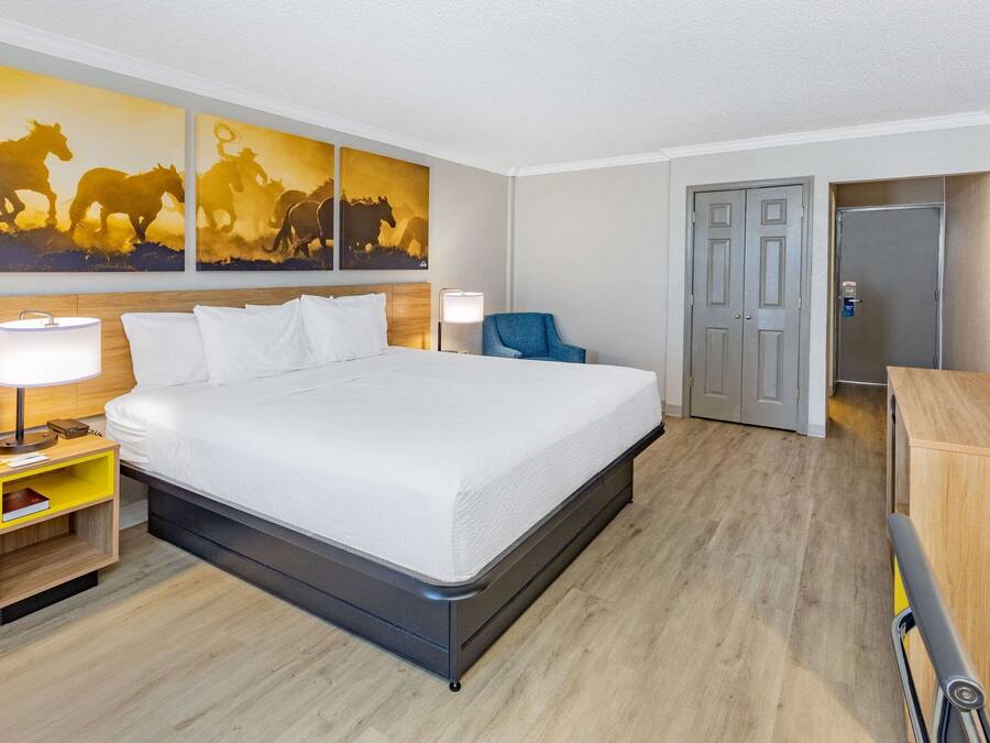 A hotel room with a large bed, bedside tables, a chair, a desk, and a TV.