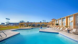 A swimming pool with lounge chairs and a building in the background.