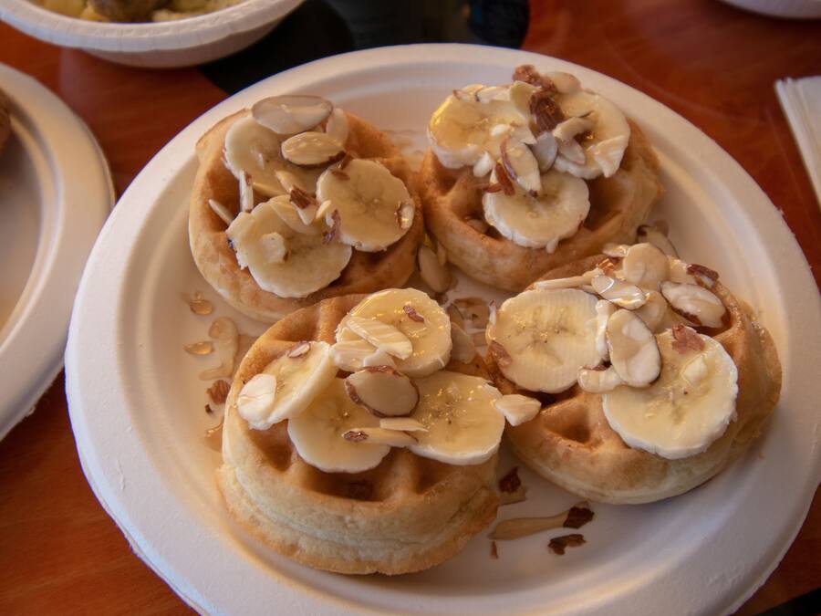 A plate of waffles topped with bananas and almonds.